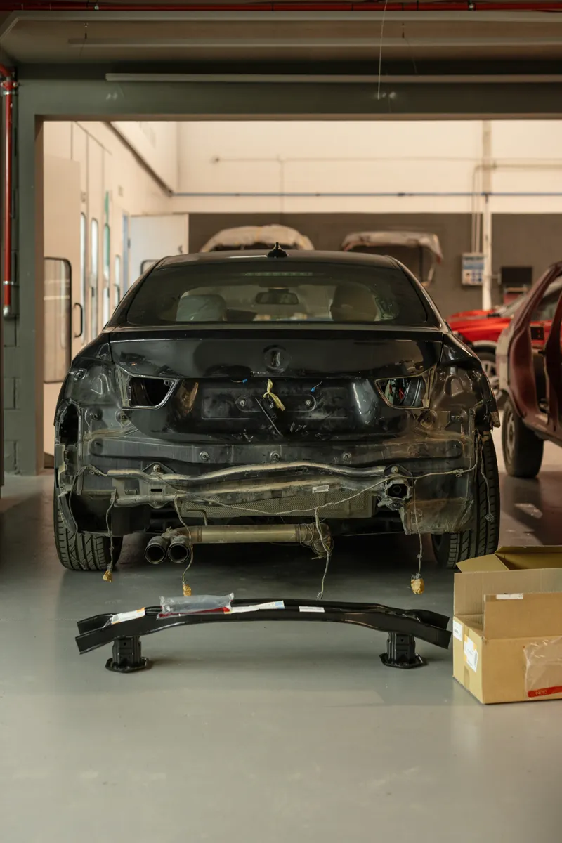 Coche accidentado con la parte trasera desmontada en el taller